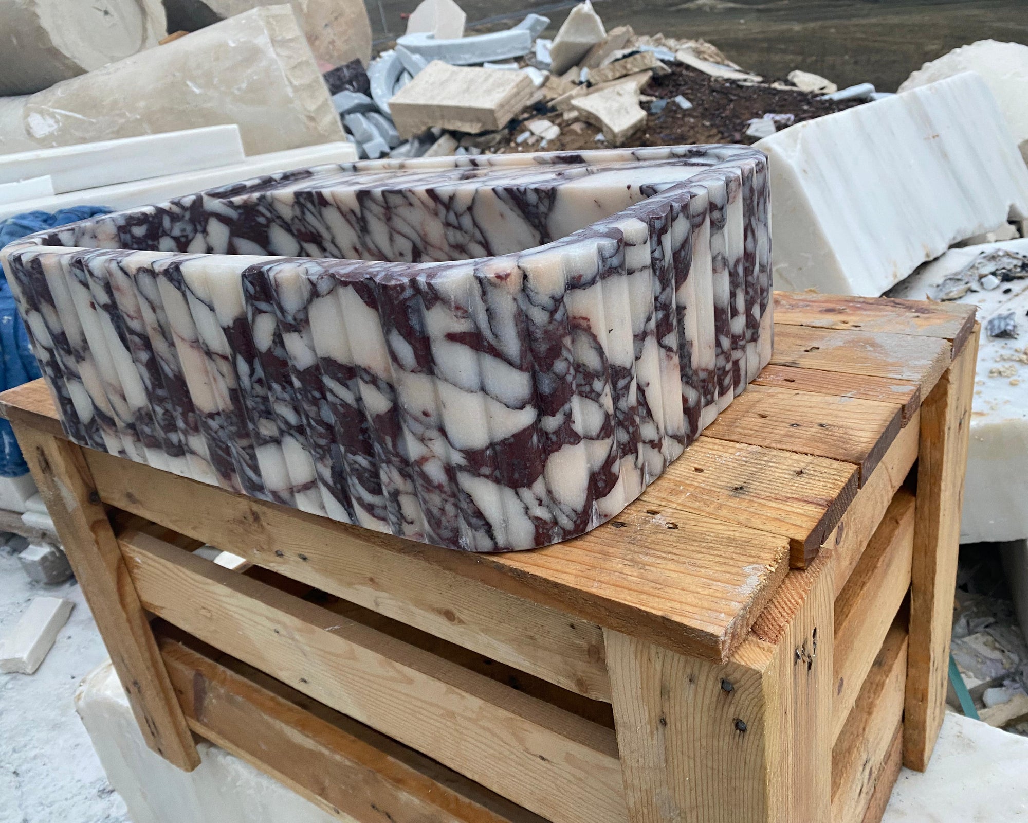 Marble basin on a wooden pallet with construction materials in the background