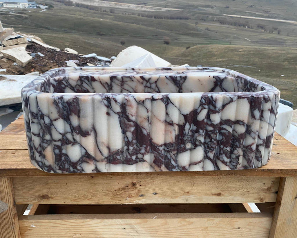 Marble-patterned stone basin on a wooden surface with a landscape in the background