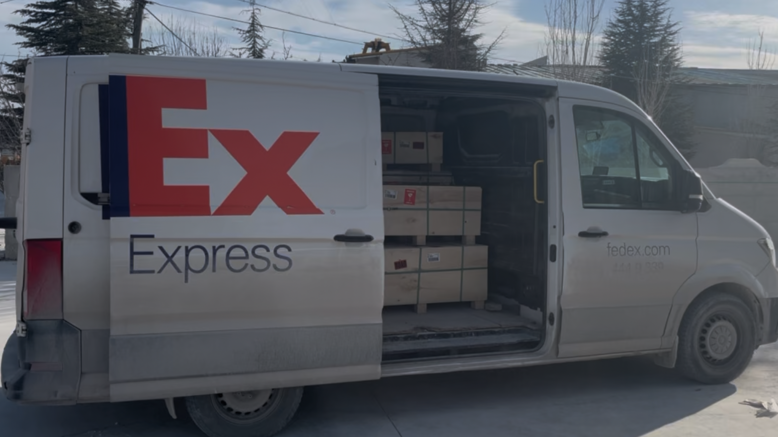 White delivery van with 'Ex Express' branding, loaded with boxes, on a snowy street.
