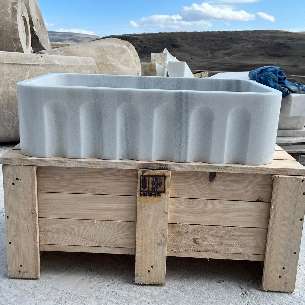 Large stone sink on a wooden pallet with a scenic background