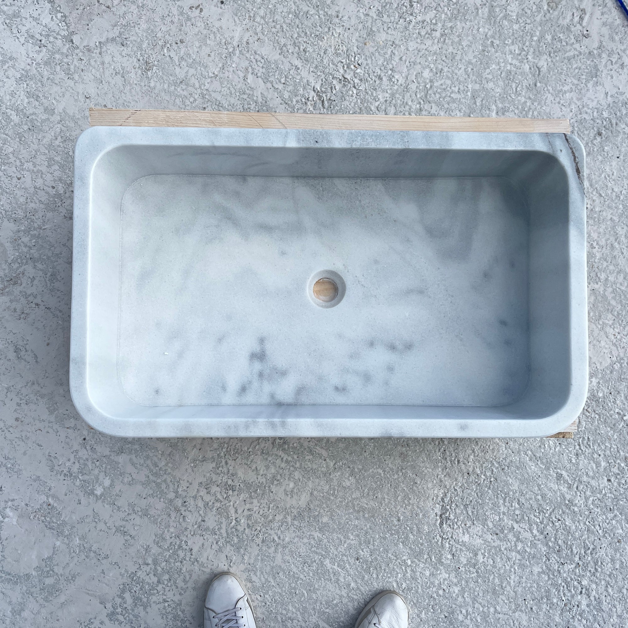 Marble sink on a concrete floor with shoes at the bottom