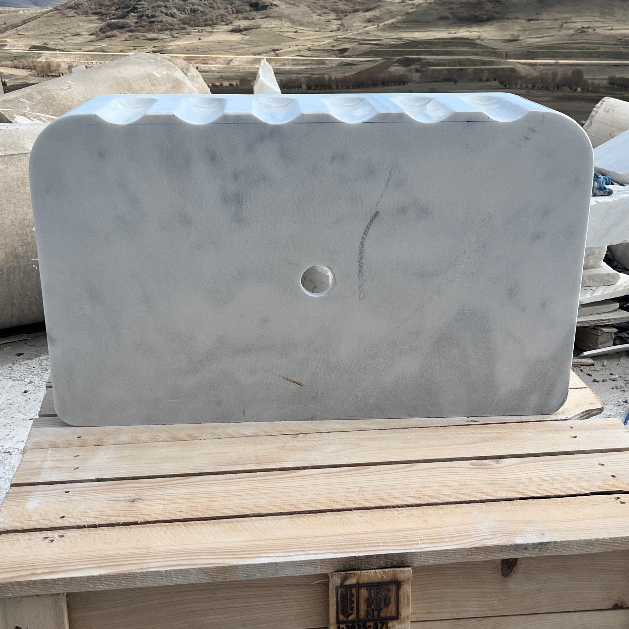 Marble basin on a wooden pallet with a mountainous landscape in the background