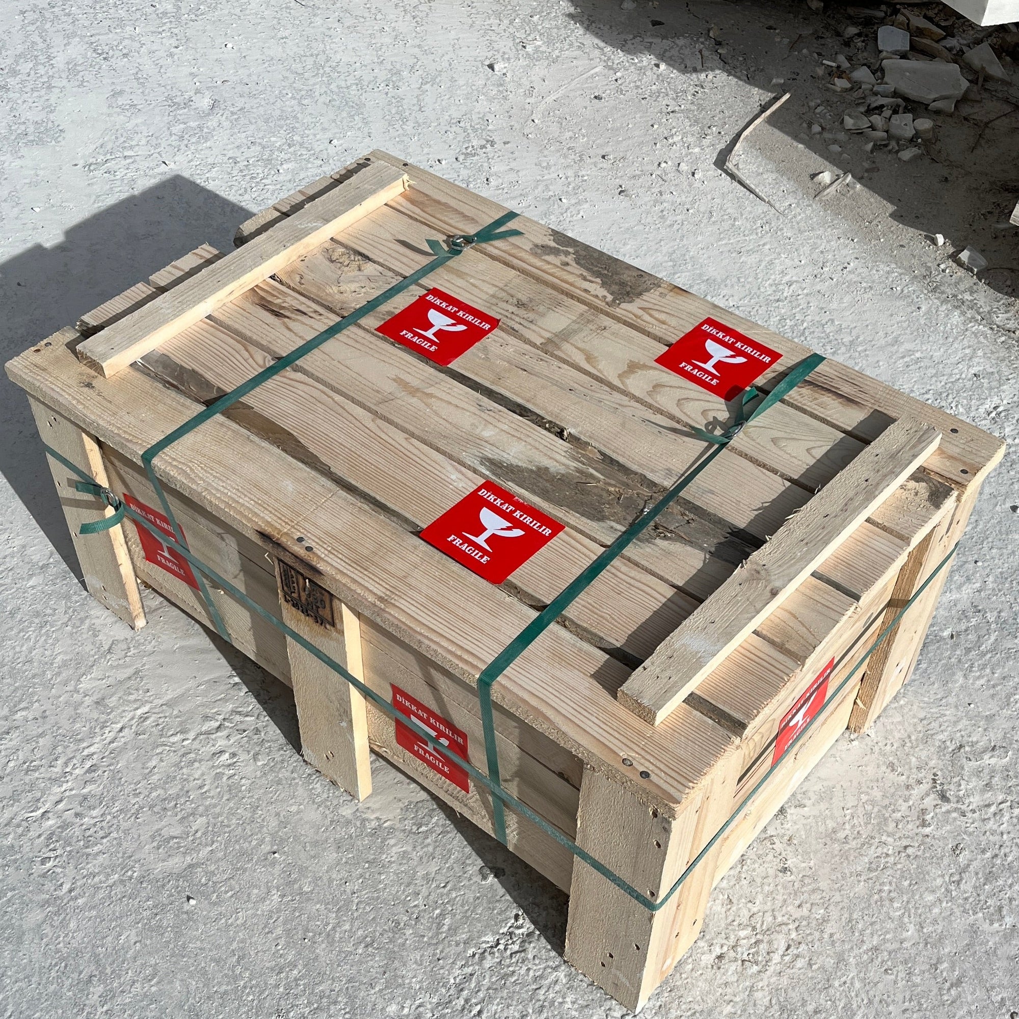 Wooden crate with straps and red labels on a concrete surface